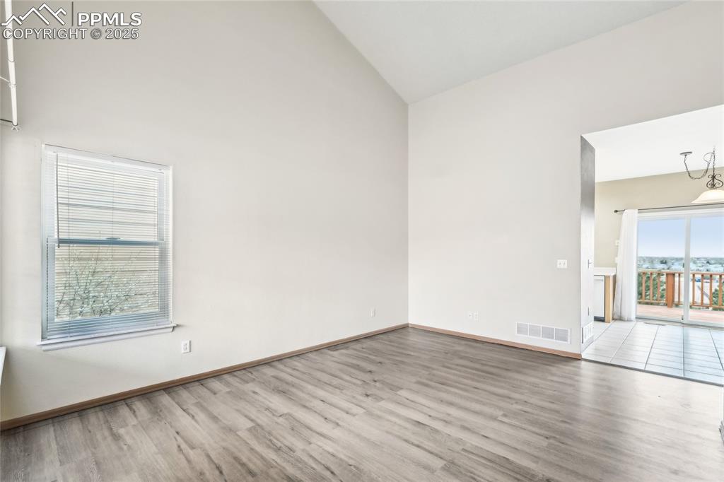 Image 5 of 49: Unfurnished room featuring high vaulted ceiling, baseboards, wood finished 