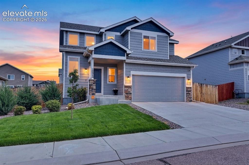 Caption: Two-story residence featuring a gray exterior with blue accents, a two-car garage, and a concrete dr