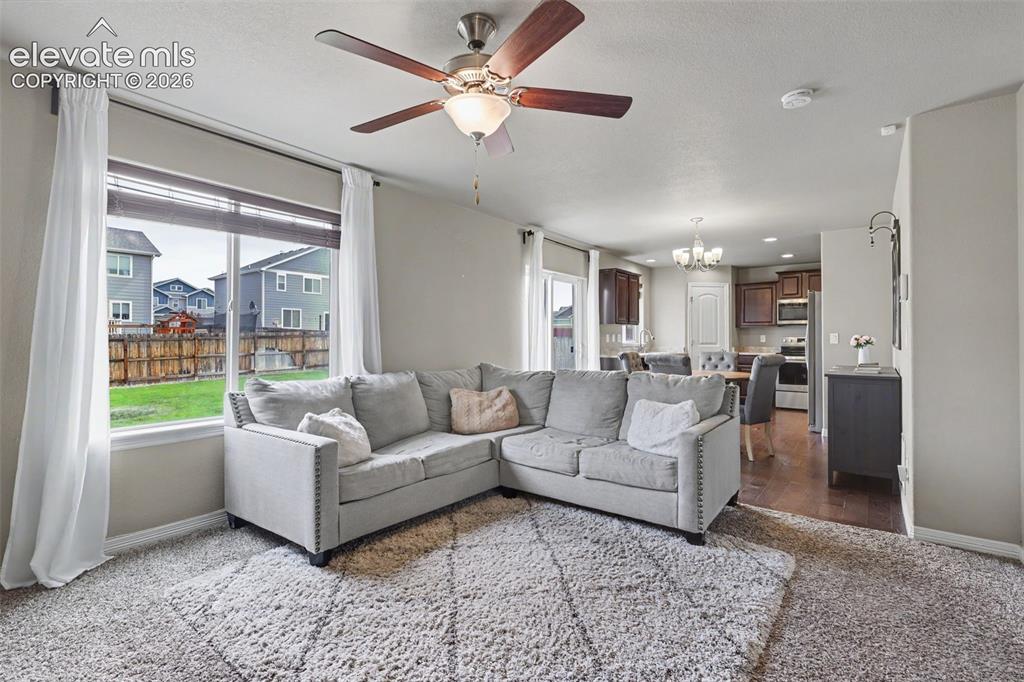 Image 11 of 40: Open-concept living area featuring a large window, ceiling fan, and carpete