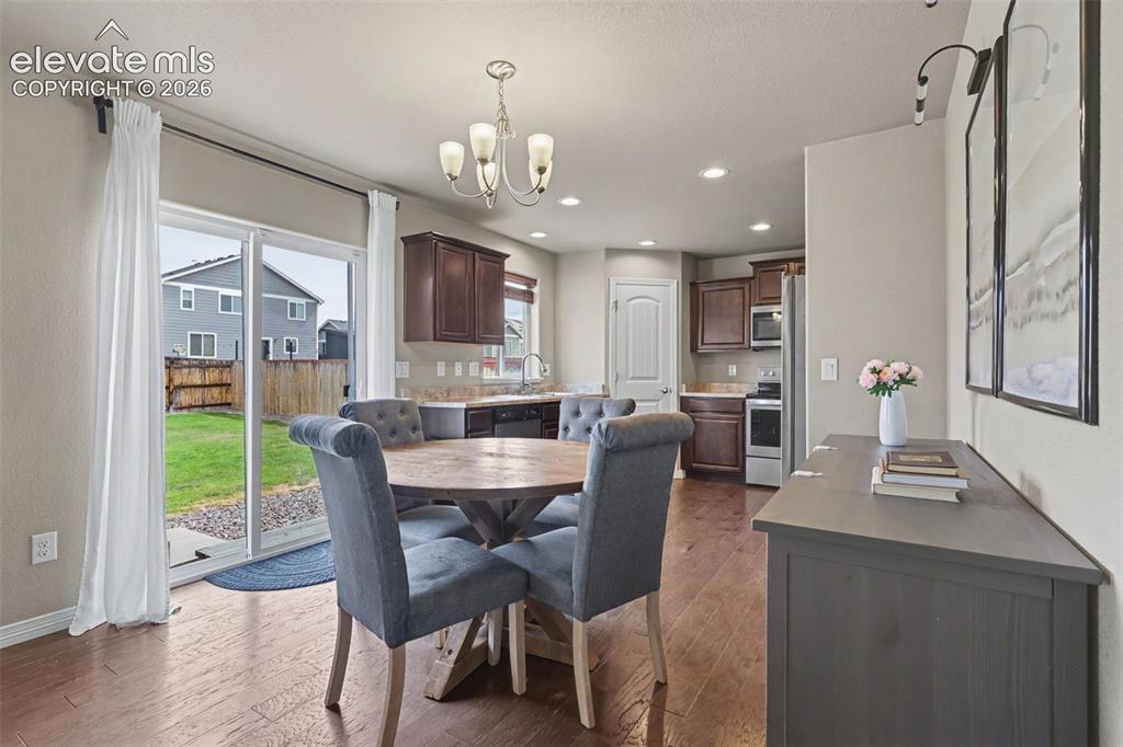 Image 14 of 40: Dining area featuring wood-finish flooring, a contemporary chandelier, and