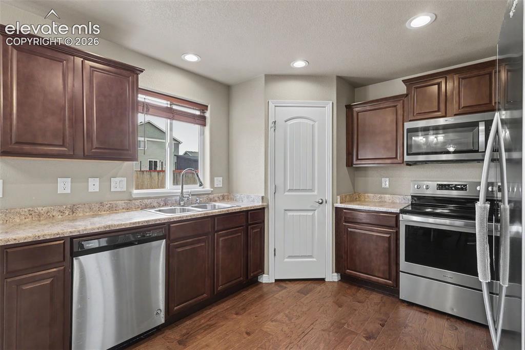 Image 16 of 40: Modern kitchen featuring stainless steel appliances, rich wood cabinetry, l