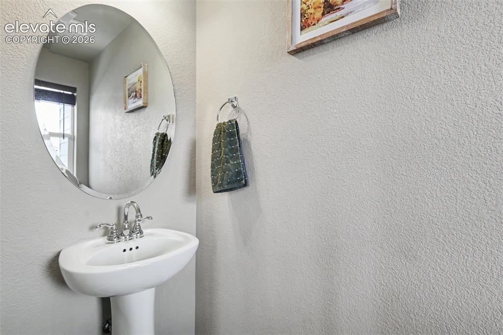 Image 18 of 40: Pedestal sink with chrome faucet, complemented by an oval frameless mirror