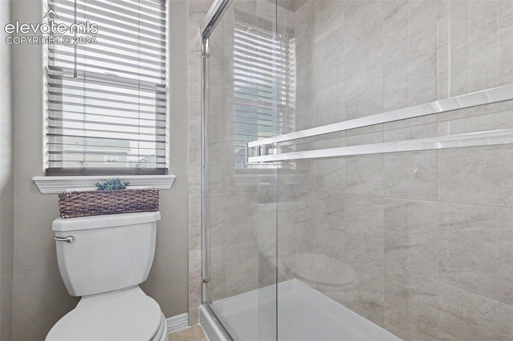 Image 23 of 40: Modern shower enclosure featuring a frameless glass door and light-toned ti