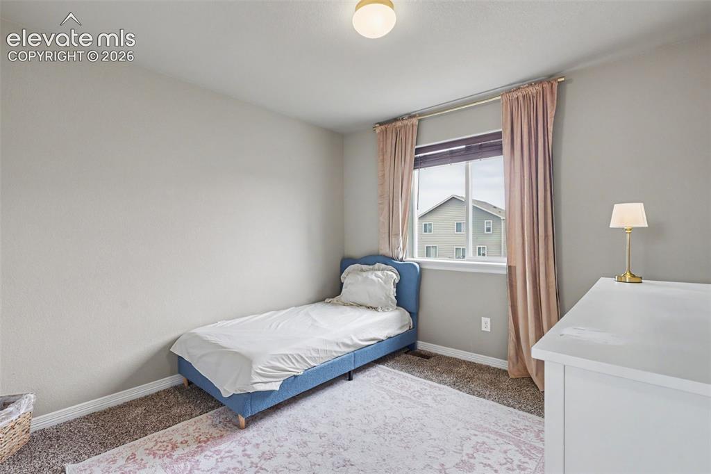 Image 27 of 40: Room featuring neutral wall tones, a single window with blinds and drapes,