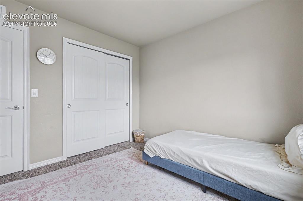 Image 28 of 40: Interior room featuring light-colored walls and grey carpet flooring