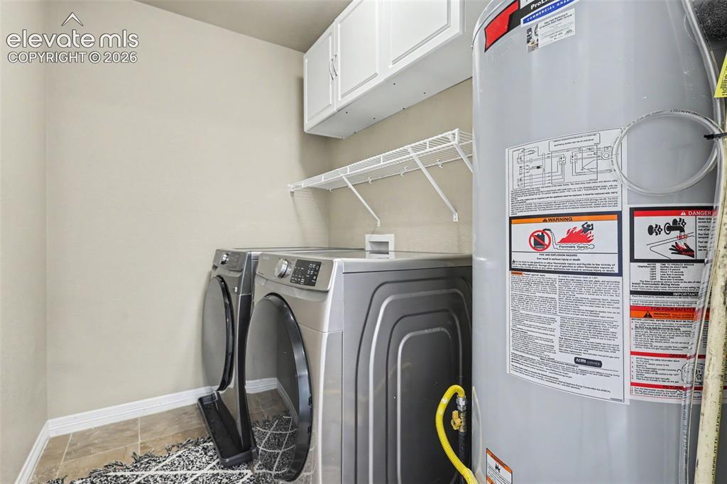 Image 29 of 40: Dedicated laundry area featuring front-loading appliances, white cabinetry