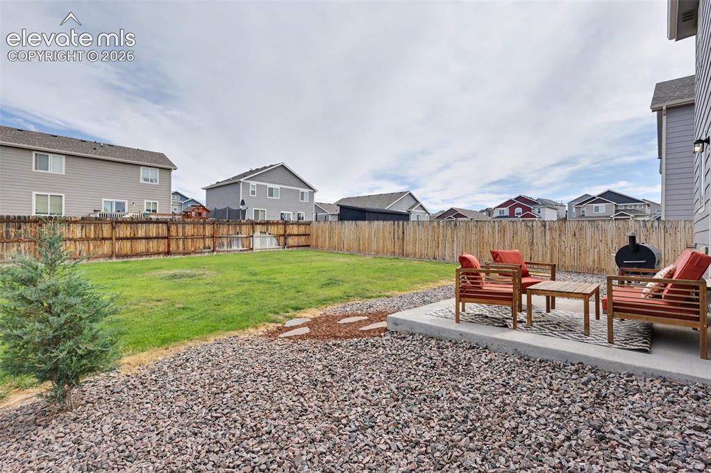 Image 30 of 40: Spacious backyard featuring a concrete patio, expansive lawn, gravel landsc