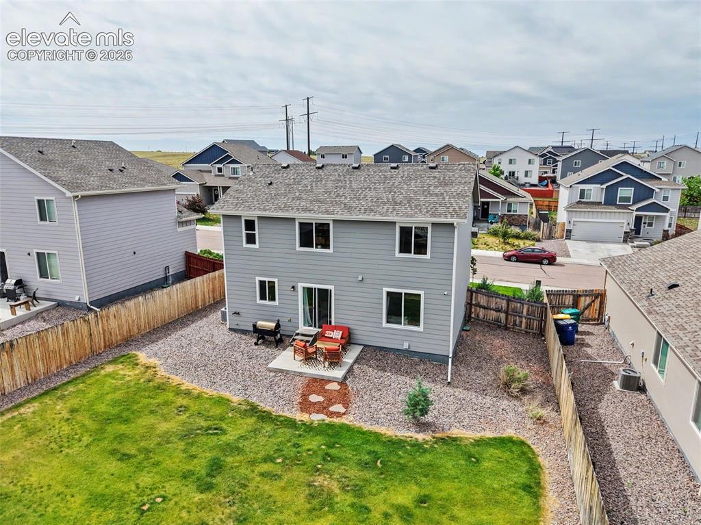 Image 34 of 40: Two-story residence featuring light gray siding and a private fenced yard