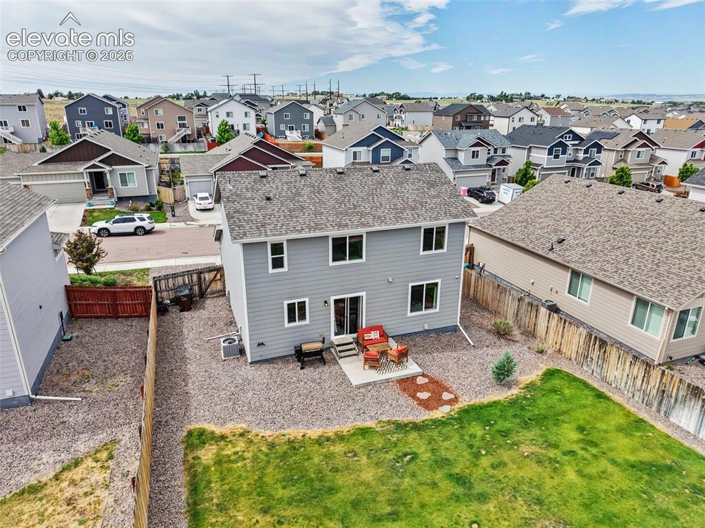 Image 36 of 40: Rear exterior featuring light gray siding, a shingle roof, and multiple win