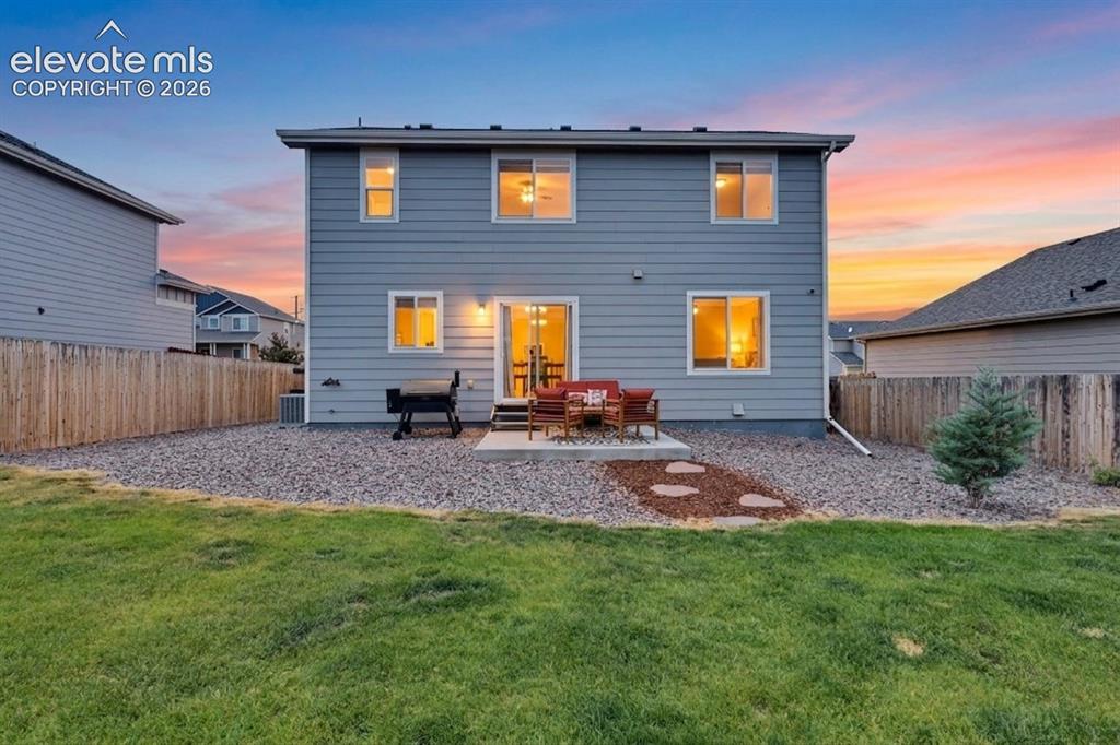 Image 4 of 40: Rear exterior featuring light blue siding, a ground-level patio, a sliding