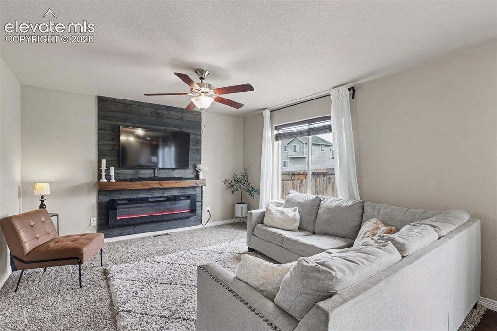 Image 9 of 40: Living room featuring a dark wood-paneled accent wall with an electric fire