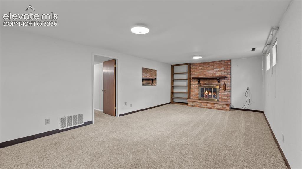 Image 20 of 36: Basement level family room has wood burning fireplace