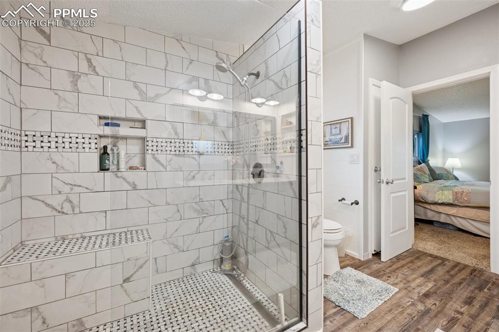 Image 28 of 33: Ensuite bathroom with a stall shower, dark wood-style floors, and a texture