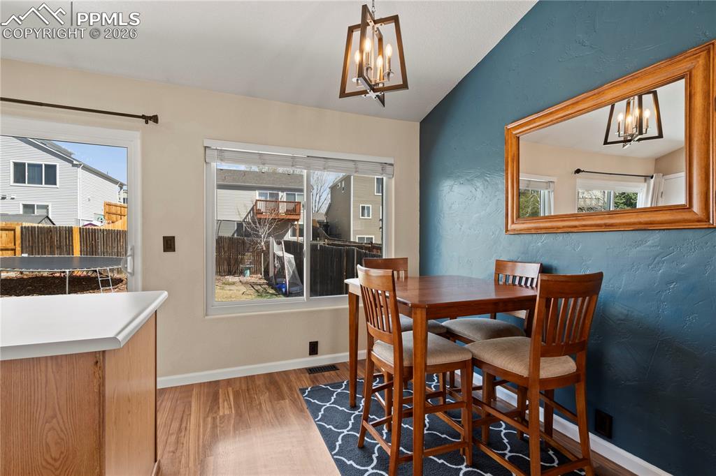 Image 12 of 27: Dining room with suspended lighting, lofted ceiling, light wood finished fl