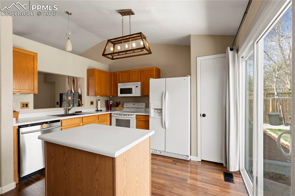 Image 13 of 27: Kitchen with white appliances, light countertops, decorative light fixtures