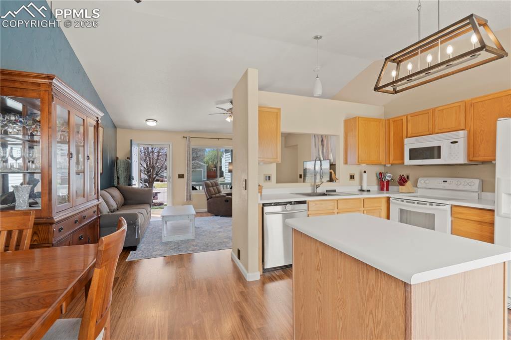 Image 14 of 27: Kitchen featuring lofted ceiling, white appliances, light countertops, a ki
