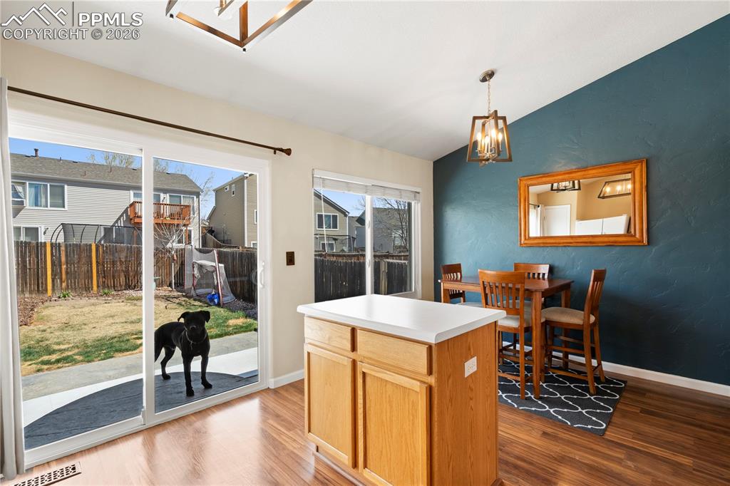 Image 16 of 27: Kitchen with lofted ceiling, light countertops, a chandelier, wood finished
