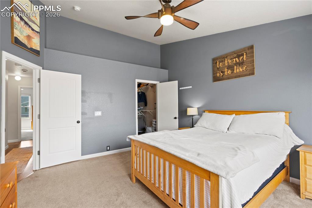 Image 22 of 27: Bedroom with light carpet, a walk in closet, and a ceiling fan