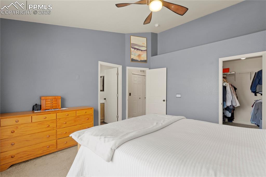 Image 23 of 27: Bedroom with vaulted ceiling, light colored carpet, ceiling fan, and a spac