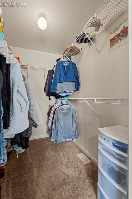Image 24 of 27: Walk in closet featuring light carpet