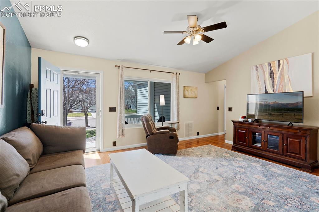 Image 8 of 27: Living room with light wood finished floors, a ceiling fan, and lofted ceil