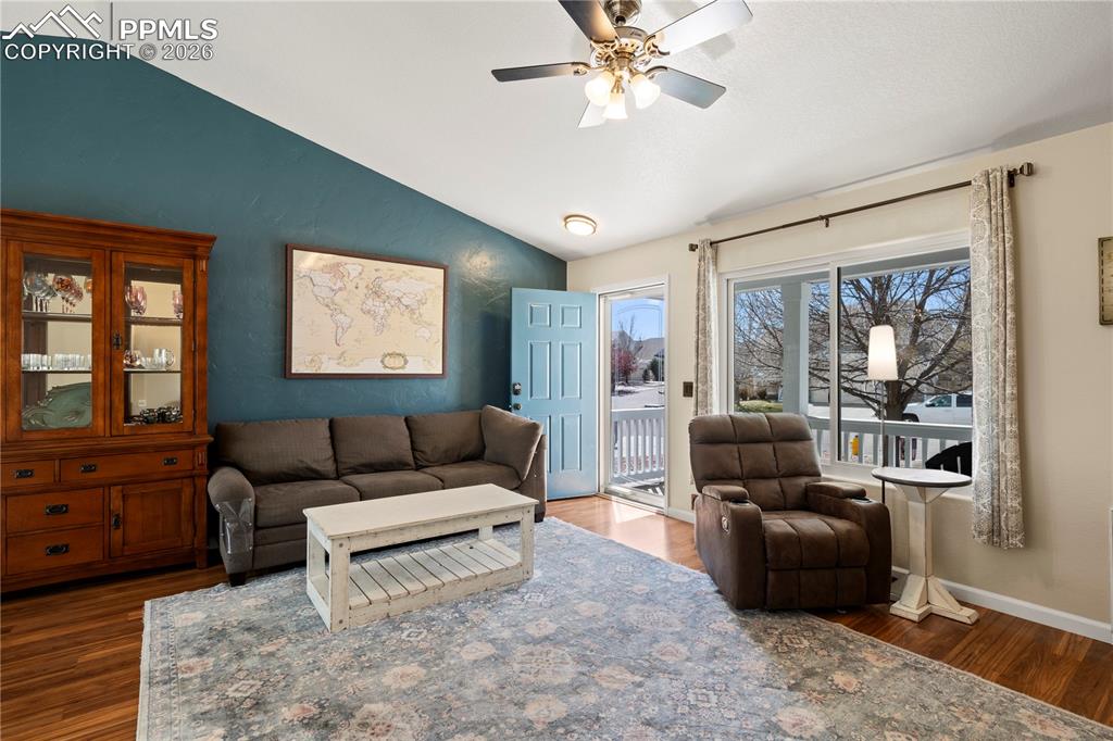 Image 9 of 27: Living room with vaulted ceiling, a ceiling fan, and dark wood-style floors