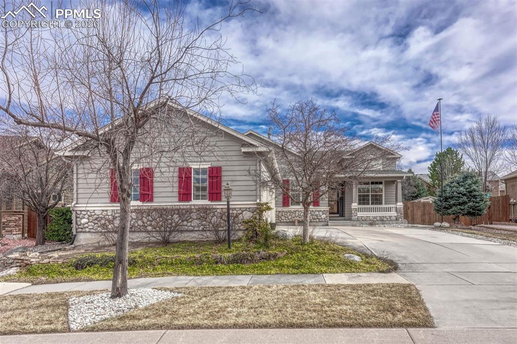 Image 3 of 45: Ranch-style home featuring covered porch, concrete driveway, and stone sidi