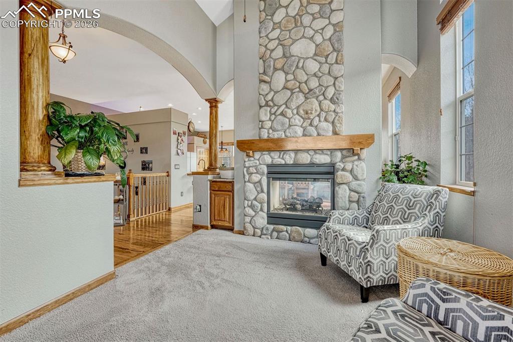 Image 4 of 45: Living area with a textured wall, light colored carpet, arched walkways, a 