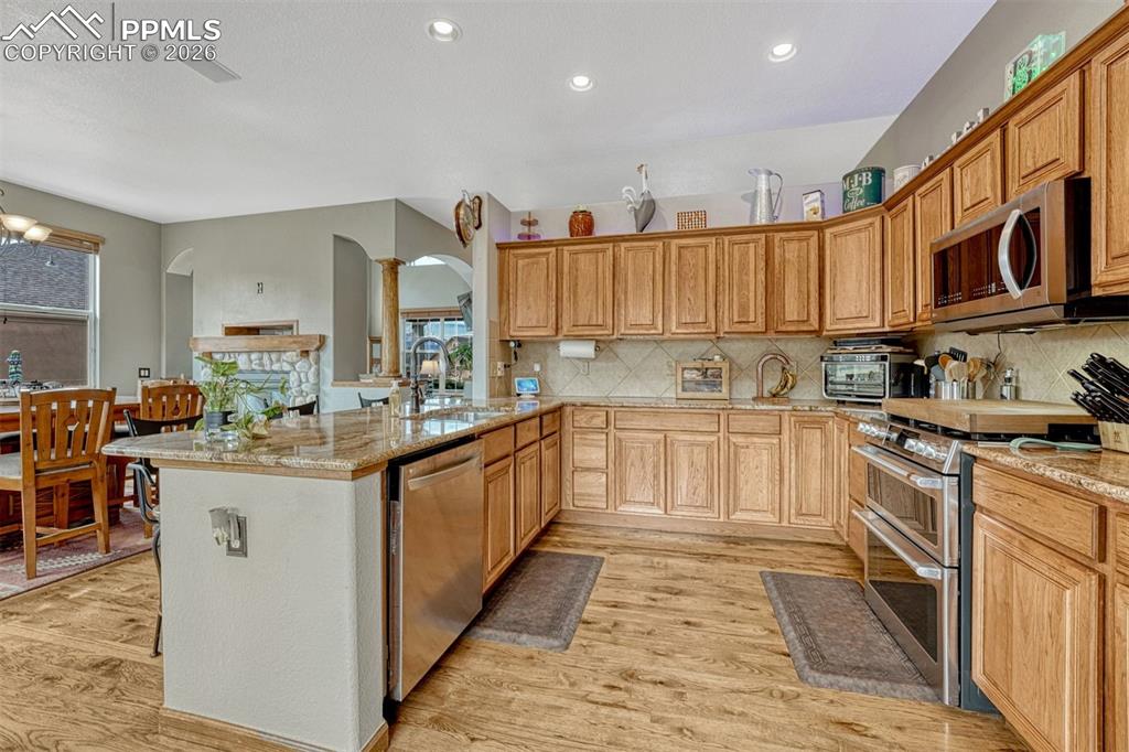 Image 8 of 45: Kitchen with stainless steel appliances, slab granite counters, wood floors