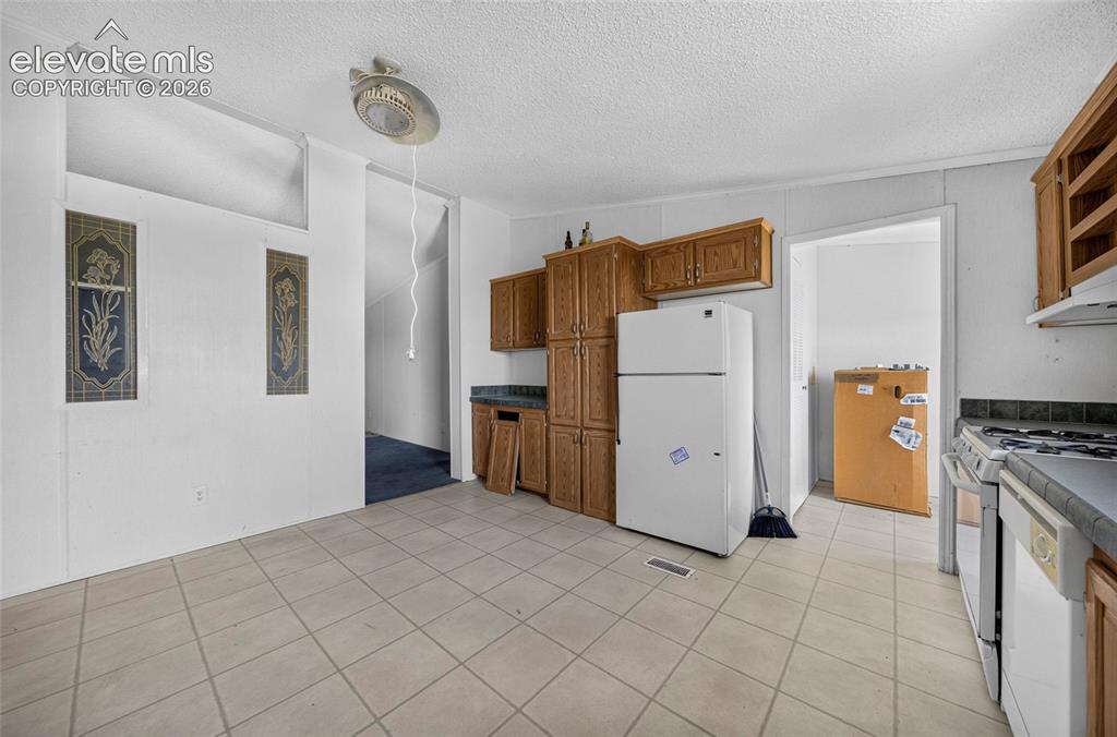 Image 10 of 41: Vinyl flooring, built-in wooden cabinetry, white refrigerator, and a gas ra