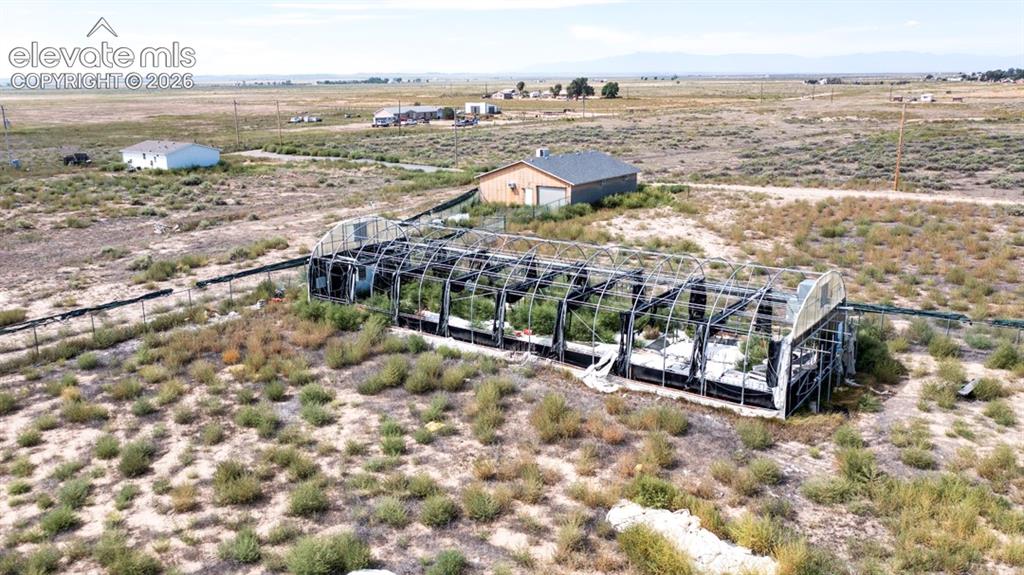 Image 29 of 41: Greenhouse structure, shop, fenced perimeter, and expansive open terrain