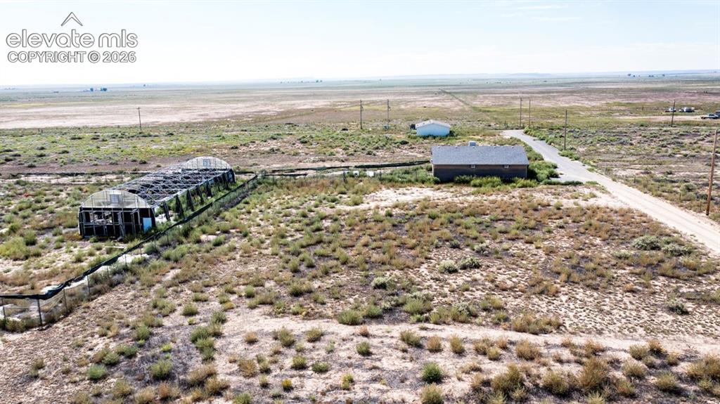 Image 39 of 41: Greenhouse structure, shop, fenced perimeter, and expansive open terrain