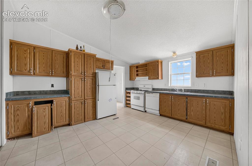 Image 8 of 41: Kitchen featuring extensive wood cabinetry, vinyl flooring, white appliance