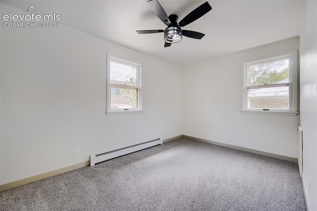 Image 17 of 41: Neutral carpet flooring, white walls, and a black ceiling fan with integrat
