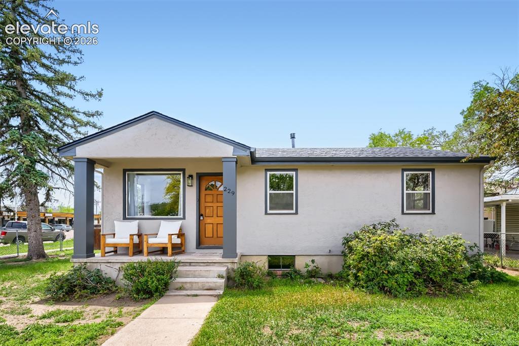 Image 2 of 41: Stucco exterior with a peaked entry, wood-finish front door, and dark-frame