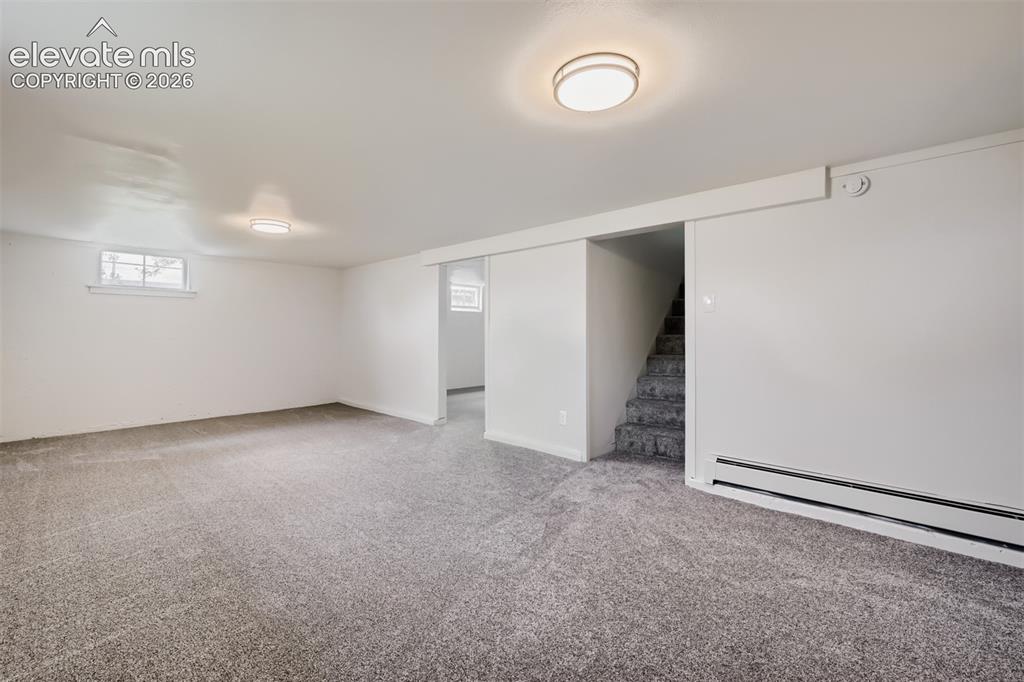 Image 27 of 41: Spacious room with gray carpet, white walls, flush mount lighting, and a sm