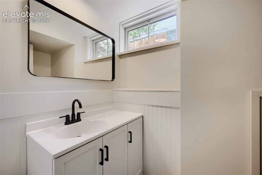 Image 31 of 41: White vanity with a solid surface countertop, undermount sink, and matte bl