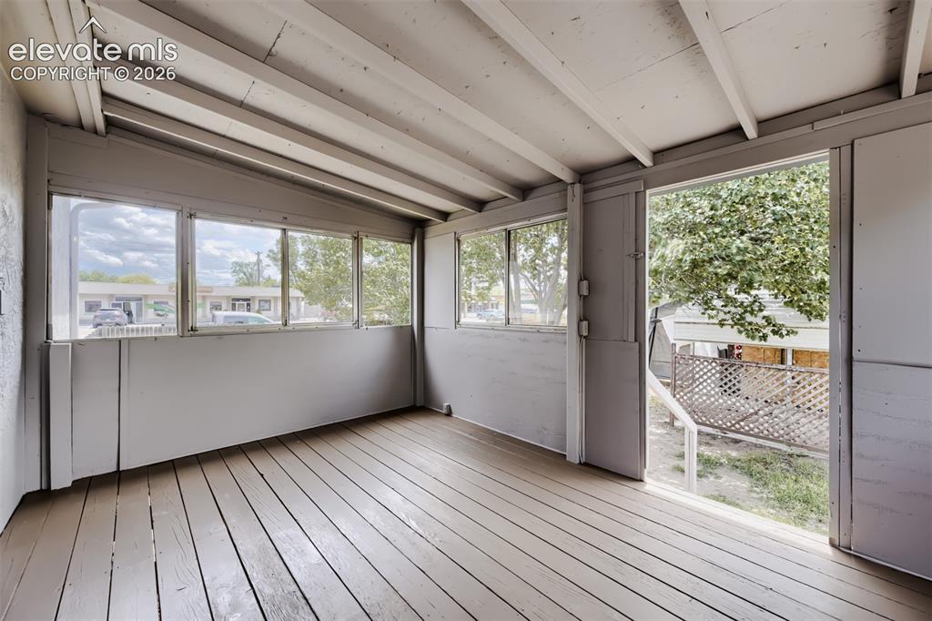 Image 34 of 41: Covered outdoor patio with exposed beam ceiling, wood-finish flooring, and 