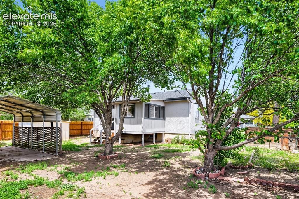Image 35 of 41: Expansive backyard featuring mature trees, a detached carport, and a wooden