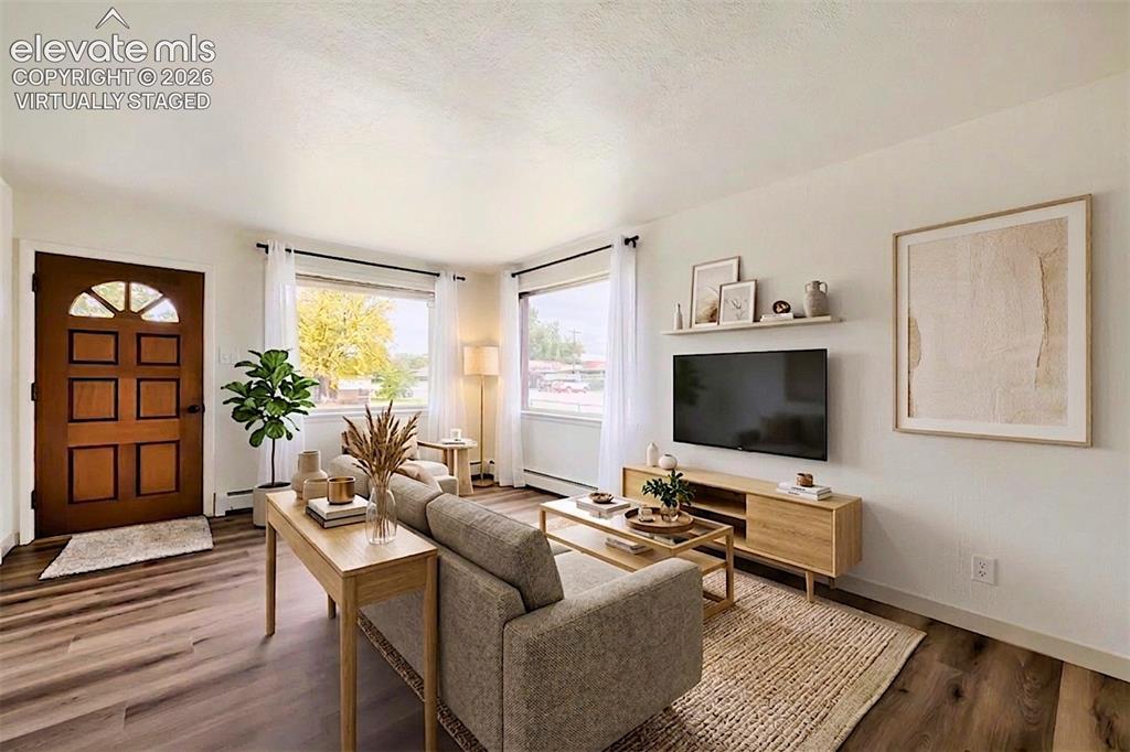 Image 4 of 41: Spacious living area featuring wood-finish flooring, a paneled front door w