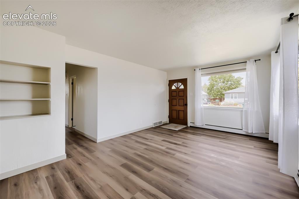 Image 6 of 41: Spacious living area showcasing wood-finish flooring throughout, abundant n