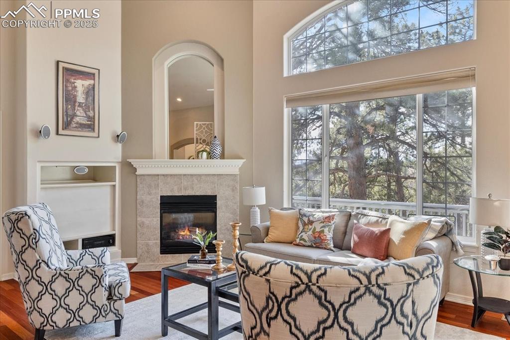 Image 2 of 46: Living room with wood finished floors, a tile fireplace, and a high ceiling