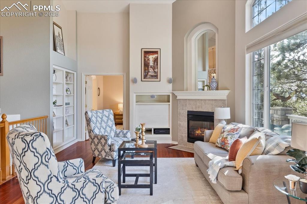 Image 3 of 46: Living room with built in shelves, a tiled fireplace, a towering ceiling, a