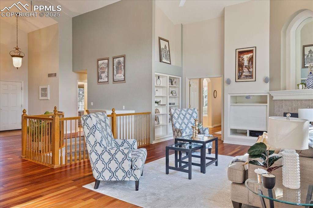 Image 5 of 46: Sitting room with a high ceiling, wood finished floors, built in features, 
