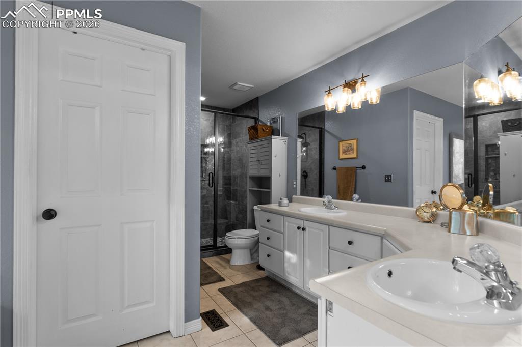 Image 26 of 38: This bathroom is beautiful with dual vanities and a river rock free standin