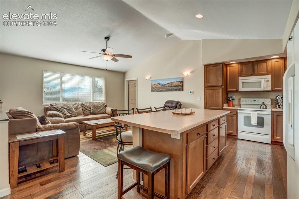 Image 10 of 50: Open-concept living area featuring wood-finish flooring, vaulted ceilings, 
