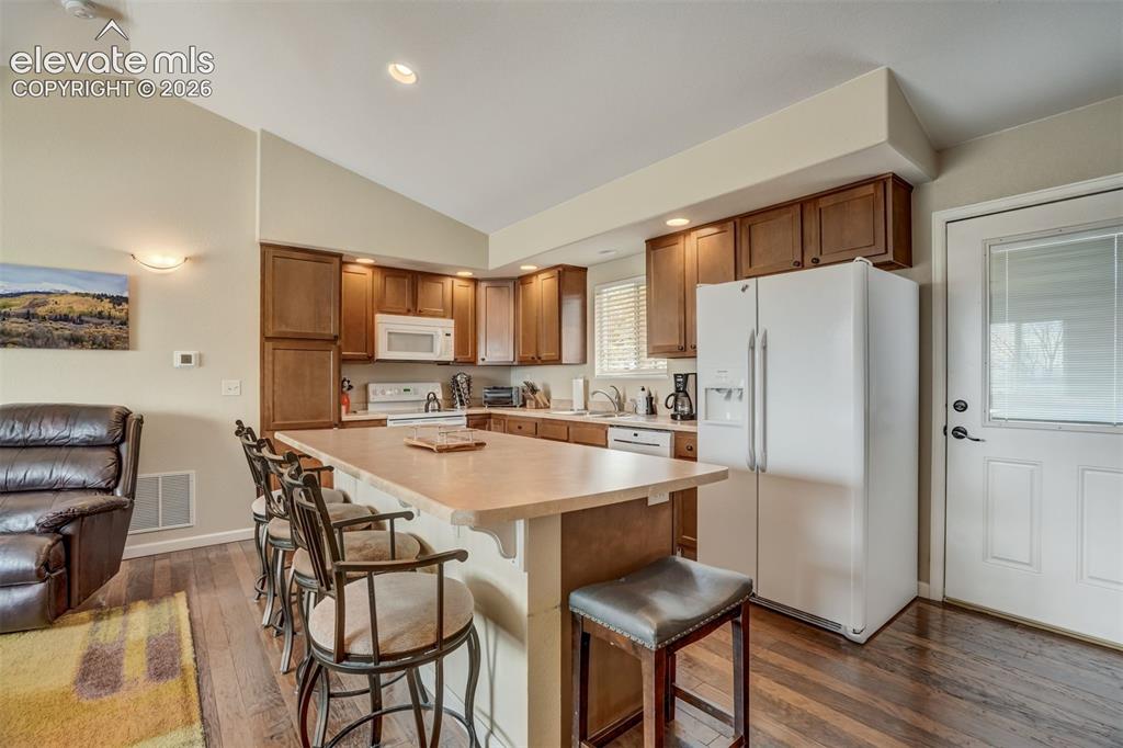 Image 11 of 50: Kitchen featuring wood-finish flooring, vaulted ceiling, recessed lighting,