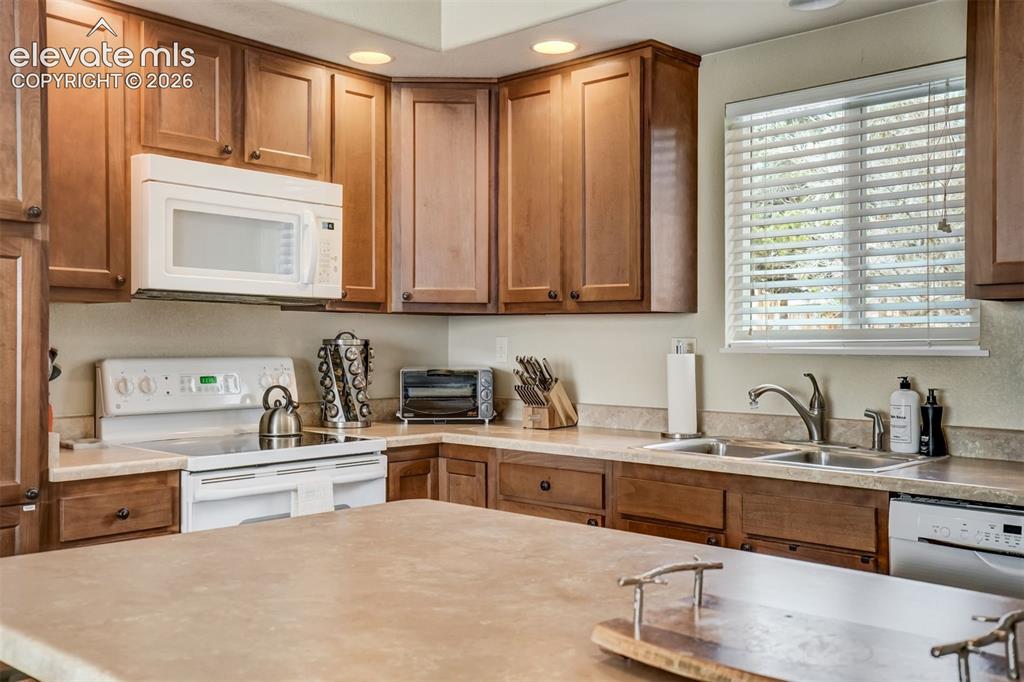 Image 13 of 50: Kitchen featuring wood cabinetry, solid surface countertops, double basin s