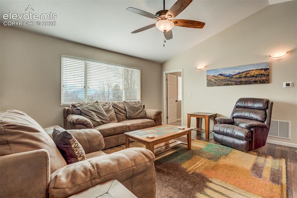 Image 18 of 50: Vaulted ceiling, ceiling fan with integrated lighting, large window with bl