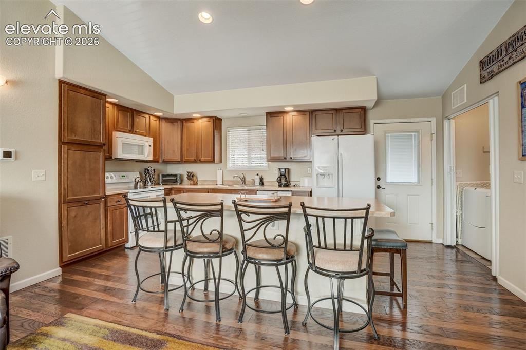 Image 21 of 50: Kitchen featuring wood-finish flooring, wood cabinetry, a breakfast bar, re